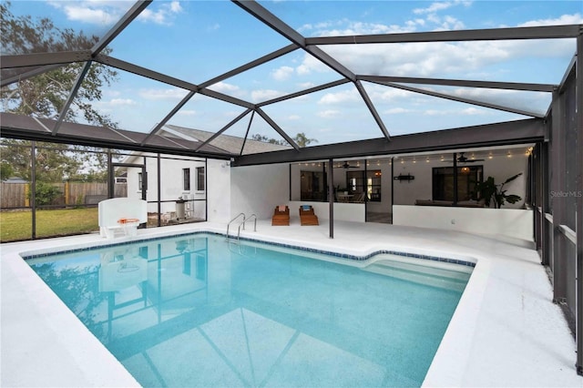 view of swimming pool with ceiling fan, glass enclosure, and a patio