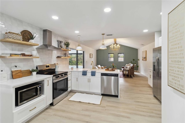 kitchen featuring white cabinets, appliances with stainless steel finishes, kitchen peninsula, and wall chimney exhaust hood