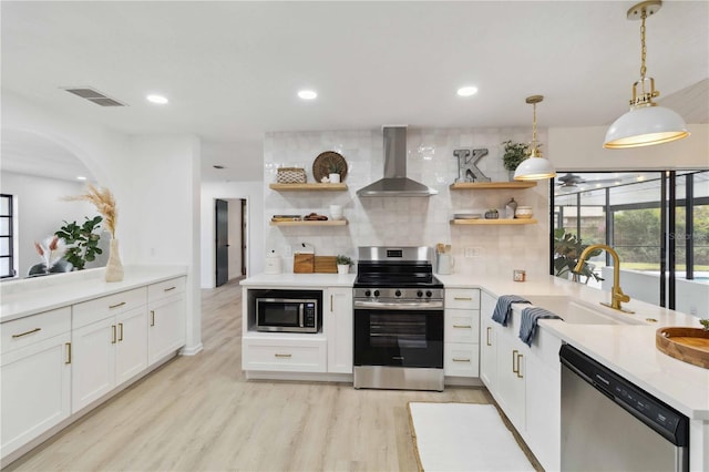 kitchen featuring white cabinetry, sink, wall chimney range hood, and stainless steel appliances