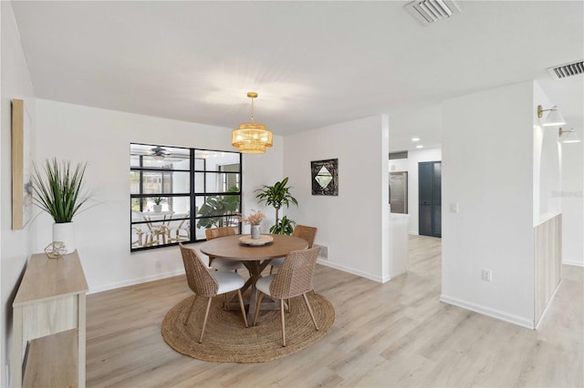 dining room with ceiling fan with notable chandelier and light hardwood / wood-style flooring