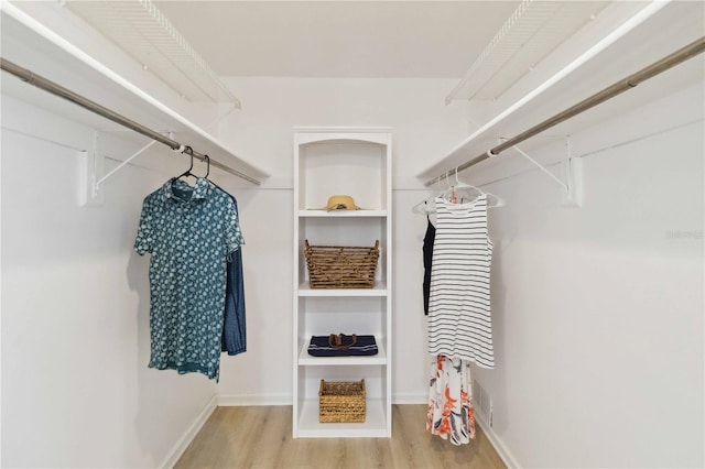 walk in closet with light hardwood / wood-style floors