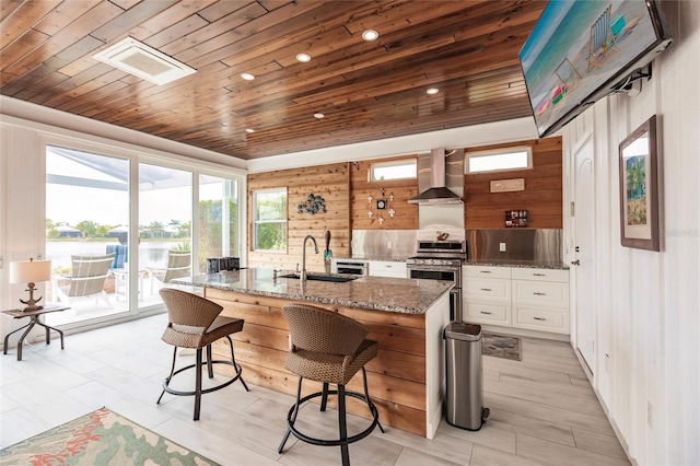 kitchen with wooden ceiling, wall chimney exhaust hood, stainless steel gas stove, and sink