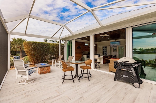 view of patio featuring glass enclosure, an outdoor bar, and a fire pit