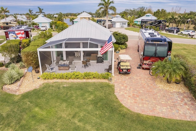 rear view of house with a patio area, a lanai, and a lawn