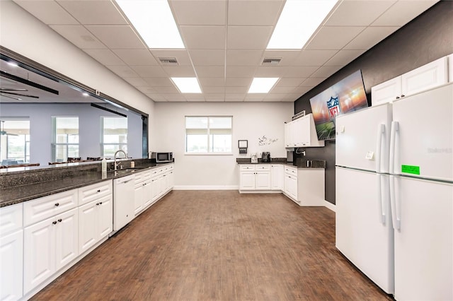 kitchen featuring sink, white cabinets, dark stone counters, and white appliances