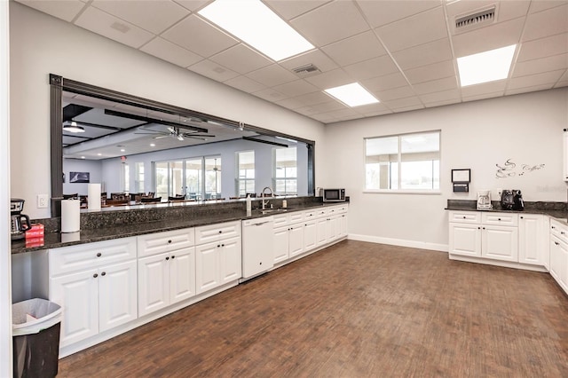 kitchen featuring ceiling fan, dark hardwood / wood-style floors, white dishwasher, white cabinetry, and dark stone counters