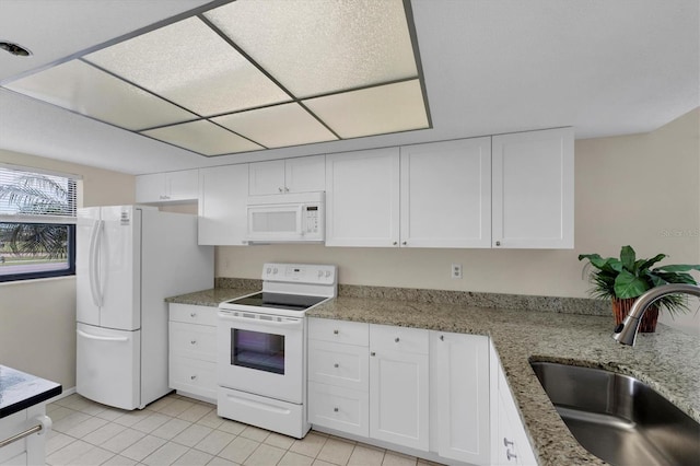 kitchen featuring light stone countertops, white appliances, white cabinetry, sink, and light tile patterned floors