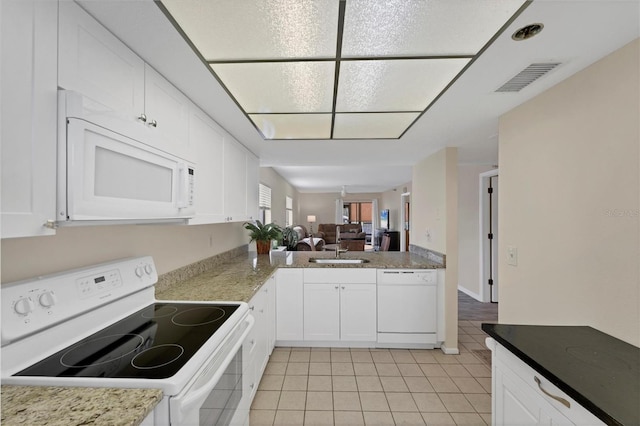 kitchen with light tile patterned floors, white cabinetry, sink, and white appliances