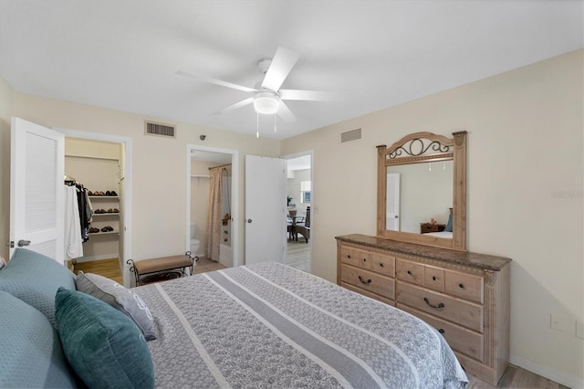 bedroom with ceiling fan, a walk in closet, a closet, and light hardwood / wood-style floors