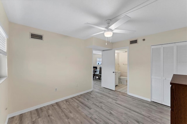 unfurnished bedroom featuring ceiling fan, a closet, ensuite bathroom, and light hardwood / wood-style flooring