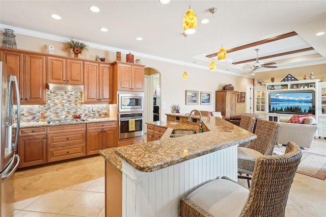 kitchen featuring sink, pendant lighting, stainless steel appliances, and a kitchen island with sink