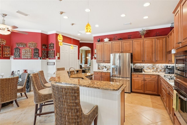 kitchen featuring kitchen peninsula, hanging light fixtures, appliances with stainless steel finishes, light stone countertops, and a breakfast bar area