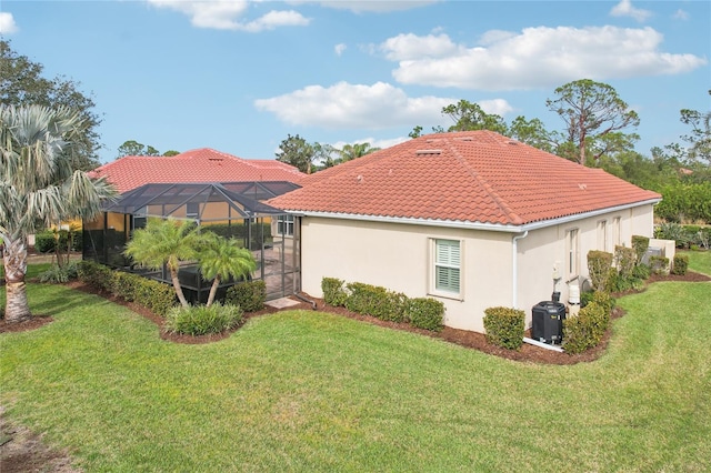 view of side of home with a lanai, central air condition unit, and a yard