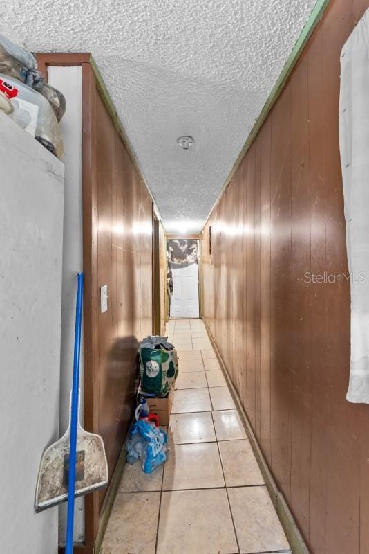 corridor featuring wooden walls and light tile patterned floors