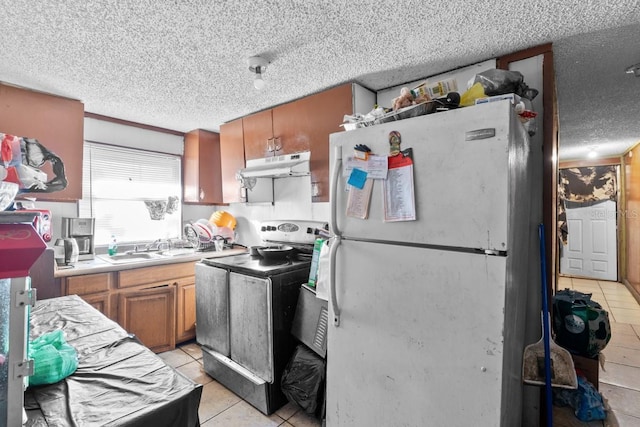 kitchen featuring sink, white fridge, stainless steel range with electric cooktop, and light tile patterned flooring