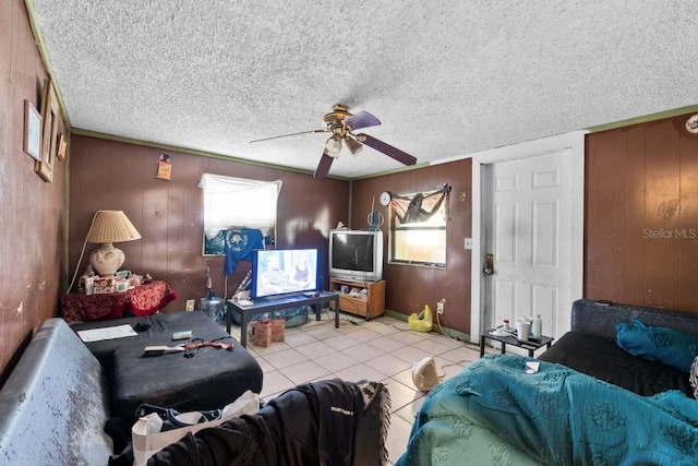 tiled living room featuring ceiling fan, wood walls, and a textured ceiling