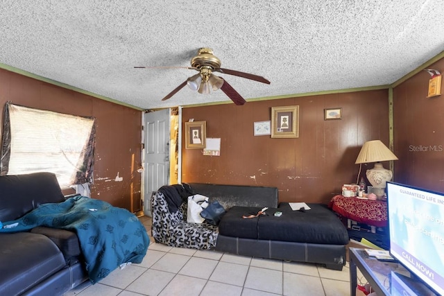 living room featuring a textured ceiling, wood walls, ceiling fan, and light tile patterned floors