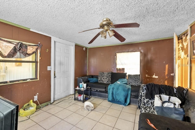 living room featuring ceiling fan, light tile patterned flooring, and a textured ceiling