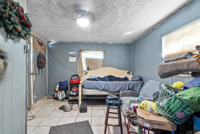 bedroom featuring a textured ceiling, wooden walls, and light tile patterned floors