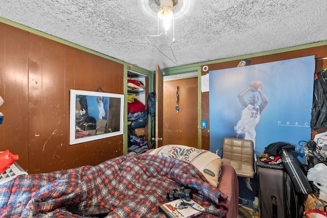 bedroom featuring wood walls and a textured ceiling