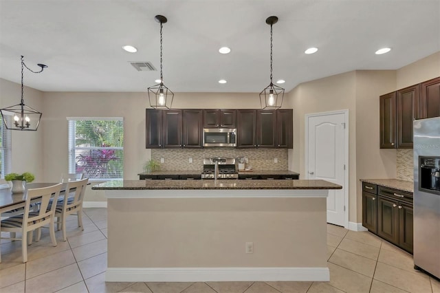 kitchen featuring decorative backsplash, appliances with stainless steel finishes, and an island with sink