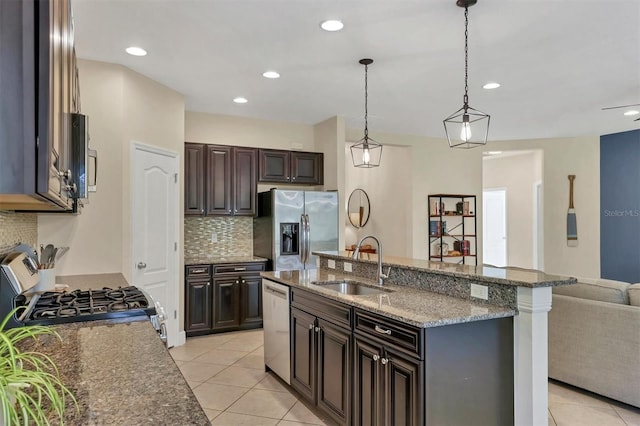 kitchen featuring appliances with stainless steel finishes, dark brown cabinetry, hanging light fixtures, and sink