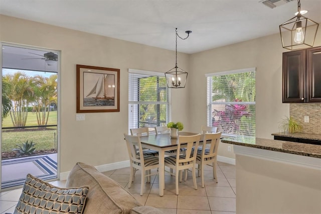 tiled dining room with a wealth of natural light and ceiling fan with notable chandelier