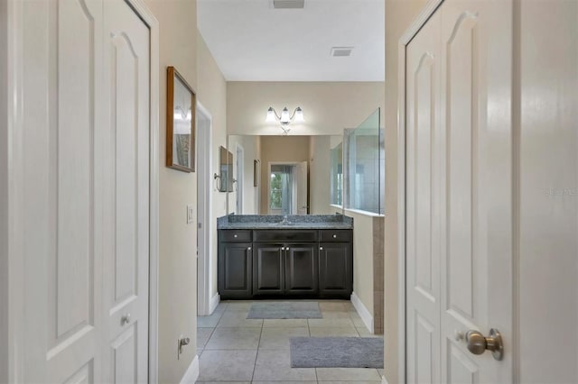 bathroom with tile patterned flooring, a shower, and vanity