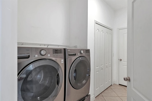 clothes washing area featuring light tile patterned floors and washing machine and dryer