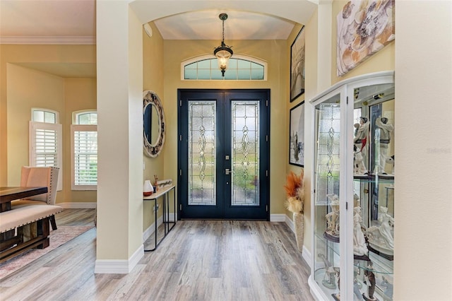 foyer entrance featuring ornamental molding, light hardwood / wood-style flooring, and french doors