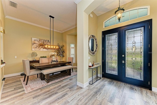 foyer featuring hardwood / wood-style flooring, crown molding, and french doors