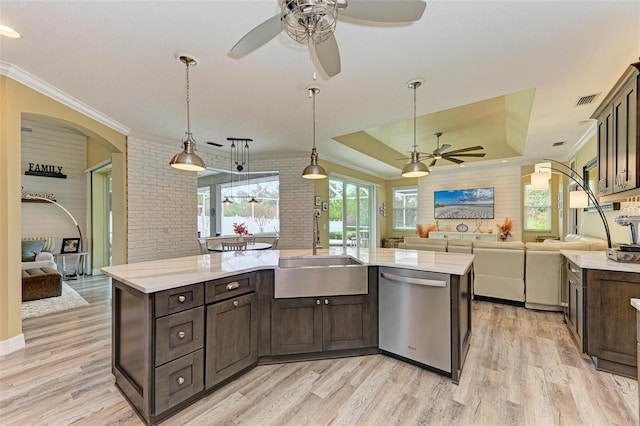 kitchen featuring dark brown cabinetry, dishwasher, an island with sink, light hardwood / wood-style floors, and a tray ceiling