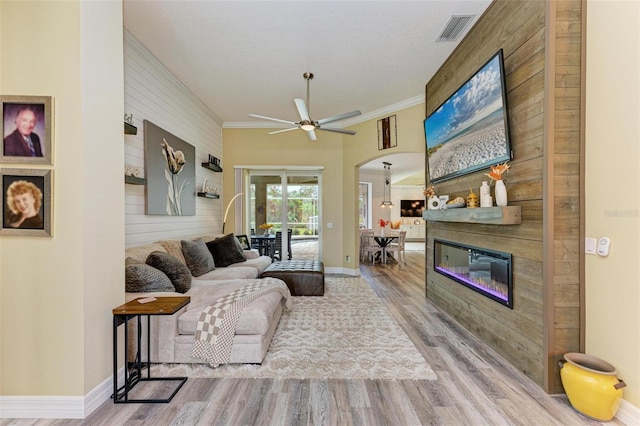 living room featuring ceiling fan, ornamental molding, a fireplace, and hardwood / wood-style flooring