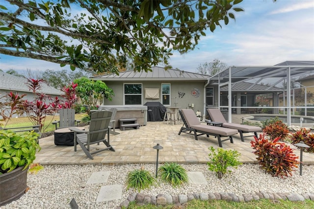 view of patio / terrace with a lanai, a hot tub, and grilling area