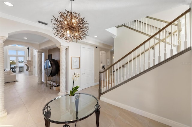 foyer entrance featuring ornate columns, crown molding, and a chandelier