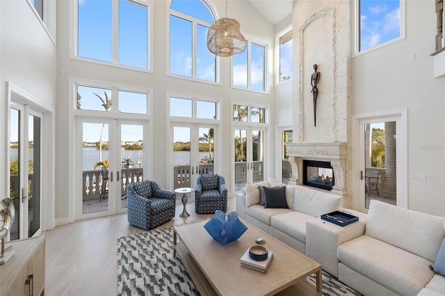 living room with a water view, french doors, a towering ceiling, and a multi sided fireplace