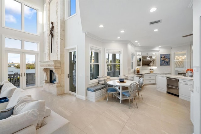 dining area with sink, a premium fireplace, crown molding, and a water view