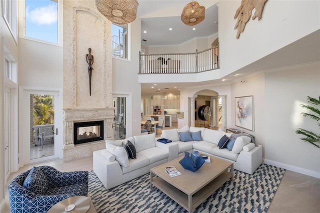 living room with crown molding, a multi sided fireplace, and a high ceiling