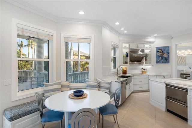 kitchen with stainless steel dishwasher, decorative backsplash, light tile patterned floors, light stone countertops, and white cabinets