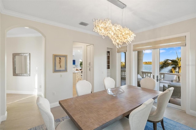 dining area with crown molding, a water view, and an inviting chandelier