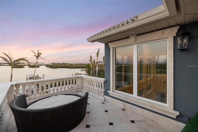 patio terrace at dusk with a balcony and a water view