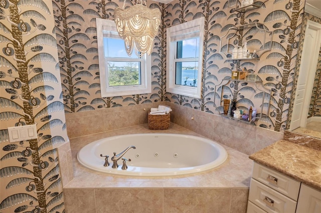 bathroom with vanity, a notable chandelier, and tiled tub