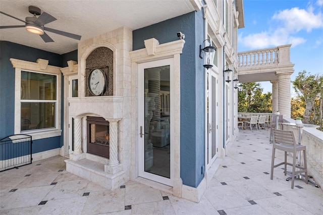 view of patio / terrace featuring ceiling fan and an outdoor fireplace