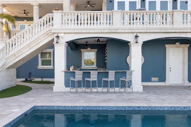 exterior space featuring ceiling fan, a balcony, a wet bar, and a patio