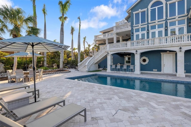 view of swimming pool with ceiling fan, a bar, and a patio