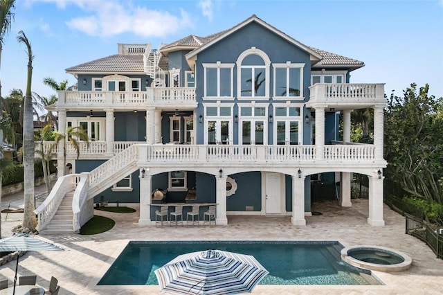 rear view of house featuring ceiling fan, a balcony, a swimming pool with hot tub, an outdoor bar, and a patio