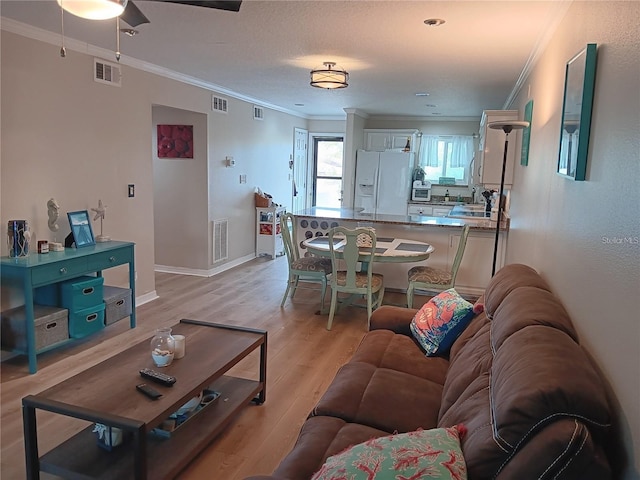 living room featuring ceiling fan, crown molding, a textured ceiling, and light hardwood / wood-style floors