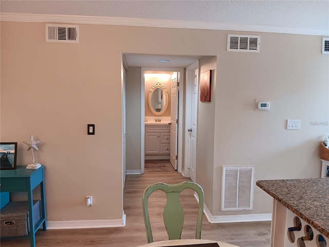 hallway featuring sink, ornamental molding, and light hardwood / wood-style flooring