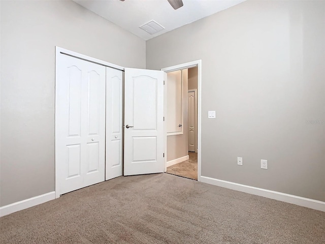 unfurnished bedroom with light colored carpet, ceiling fan, and a closet