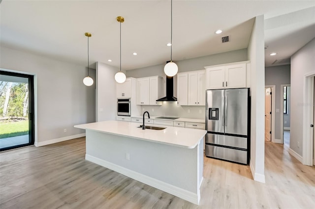 kitchen with wall chimney exhaust hood, an island with sink, pendant lighting, stainless steel appliances, and white cabinets